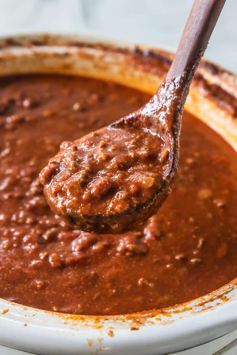 A ladle of chili scooped from a slow cooker.