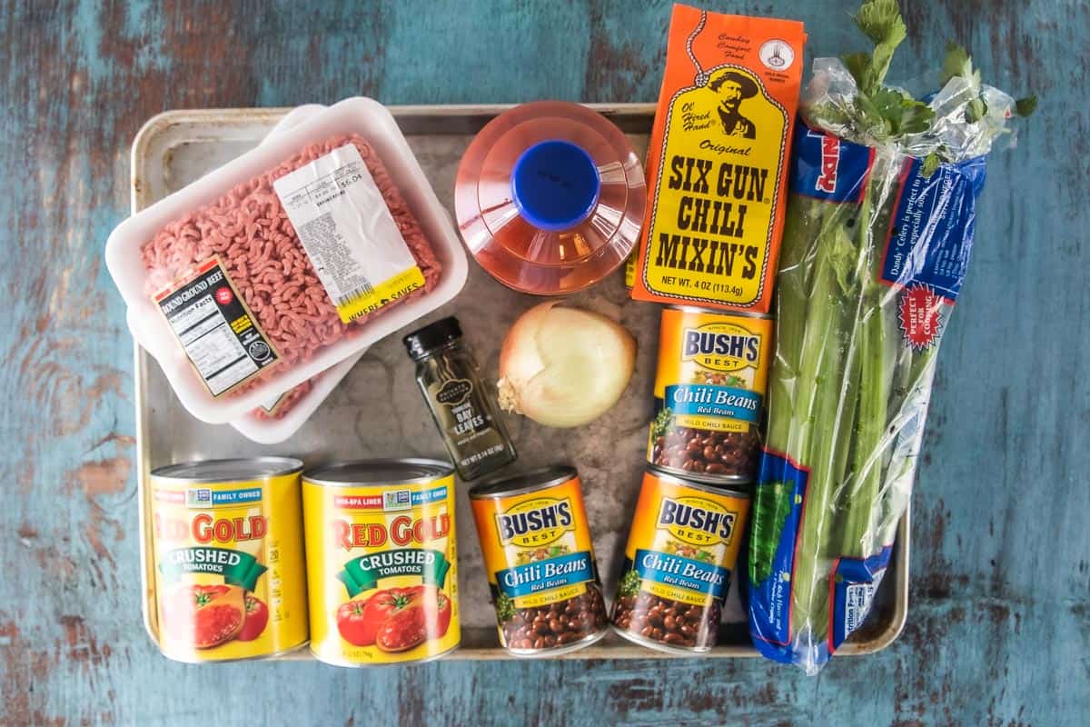 Ingredients to make slow cooker chili for halloween including crushed tomatoes, chili beans, and ground beef.