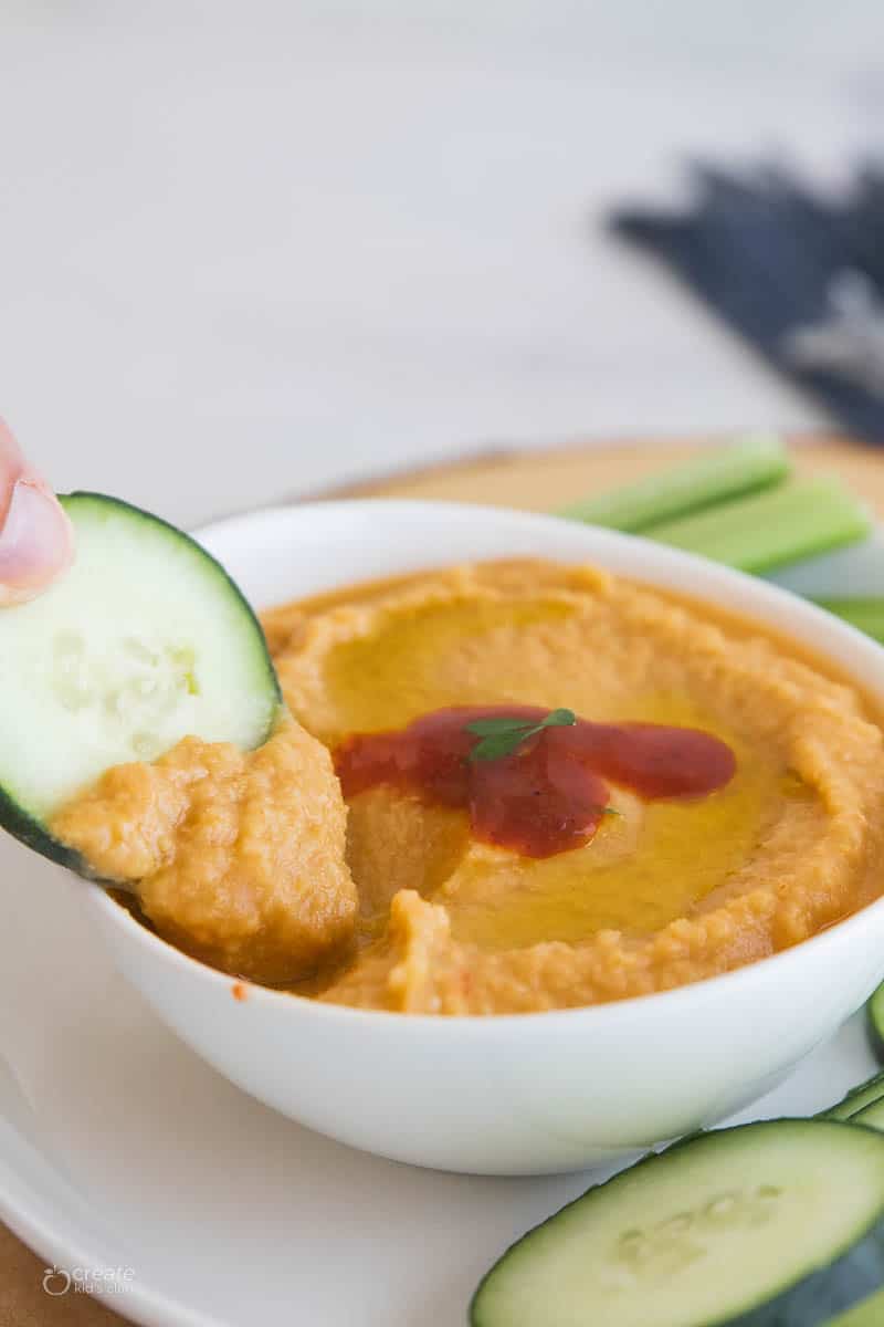 sliced cucumber dipped in hummus