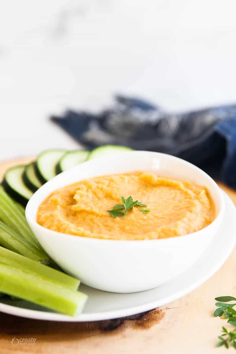 homemade hummus in bowl next to fresh vegetables