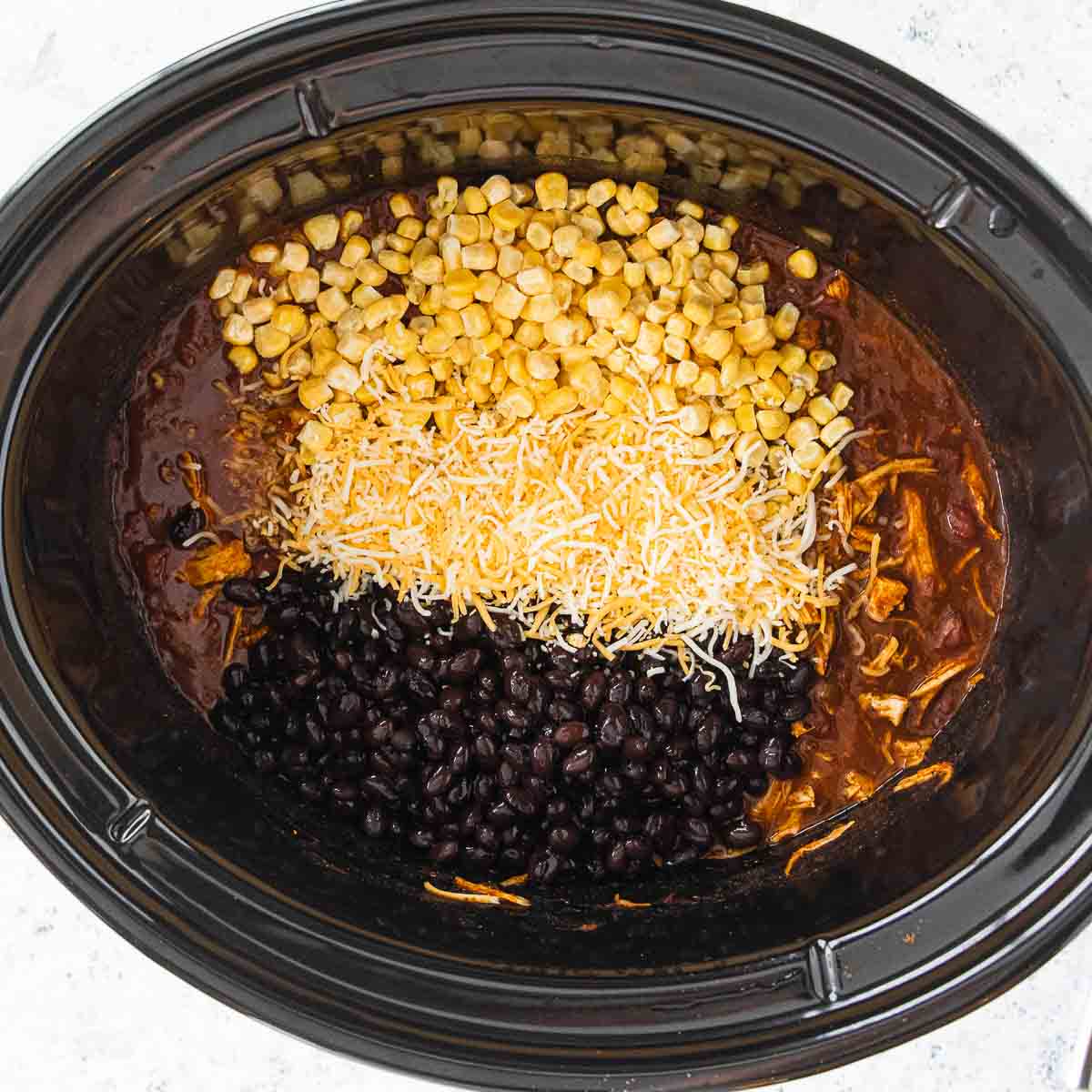 black beans, shredded cheese and corn added to chicken enchiladas