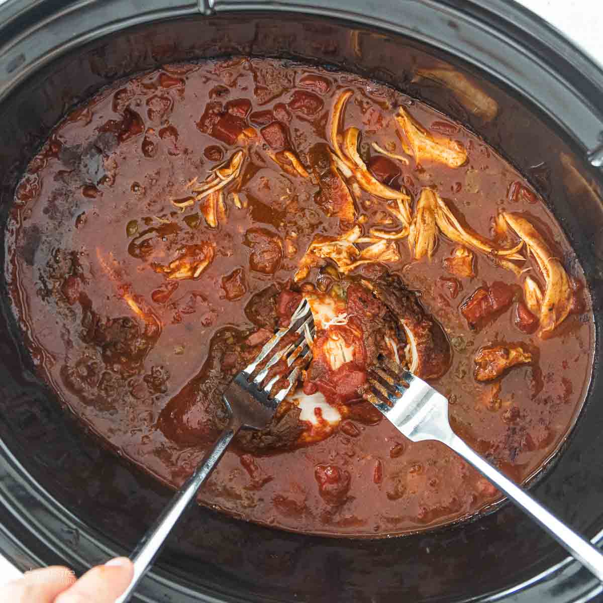 forks shredding chicken in crockpot