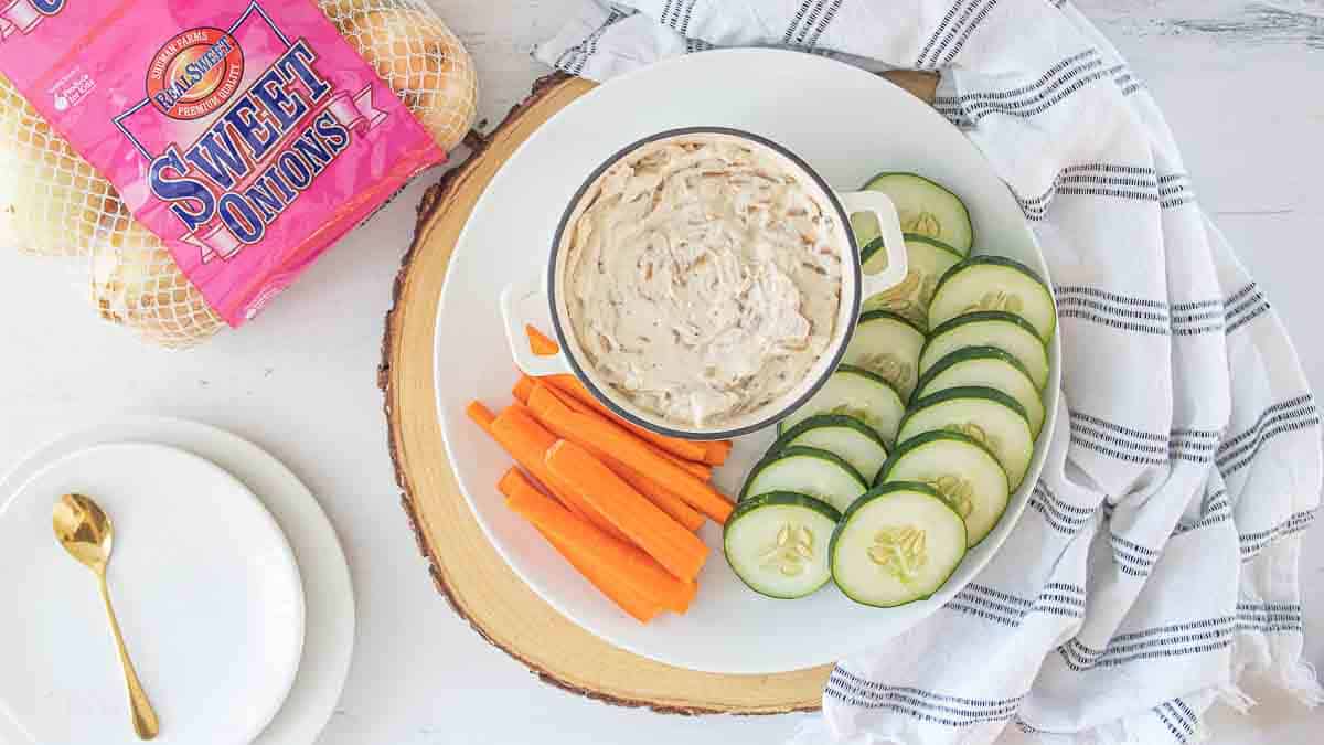 caramelized sweet onion dip in bowl next to raw veggies