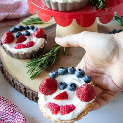 hand holding fruit tart with a snowman face
