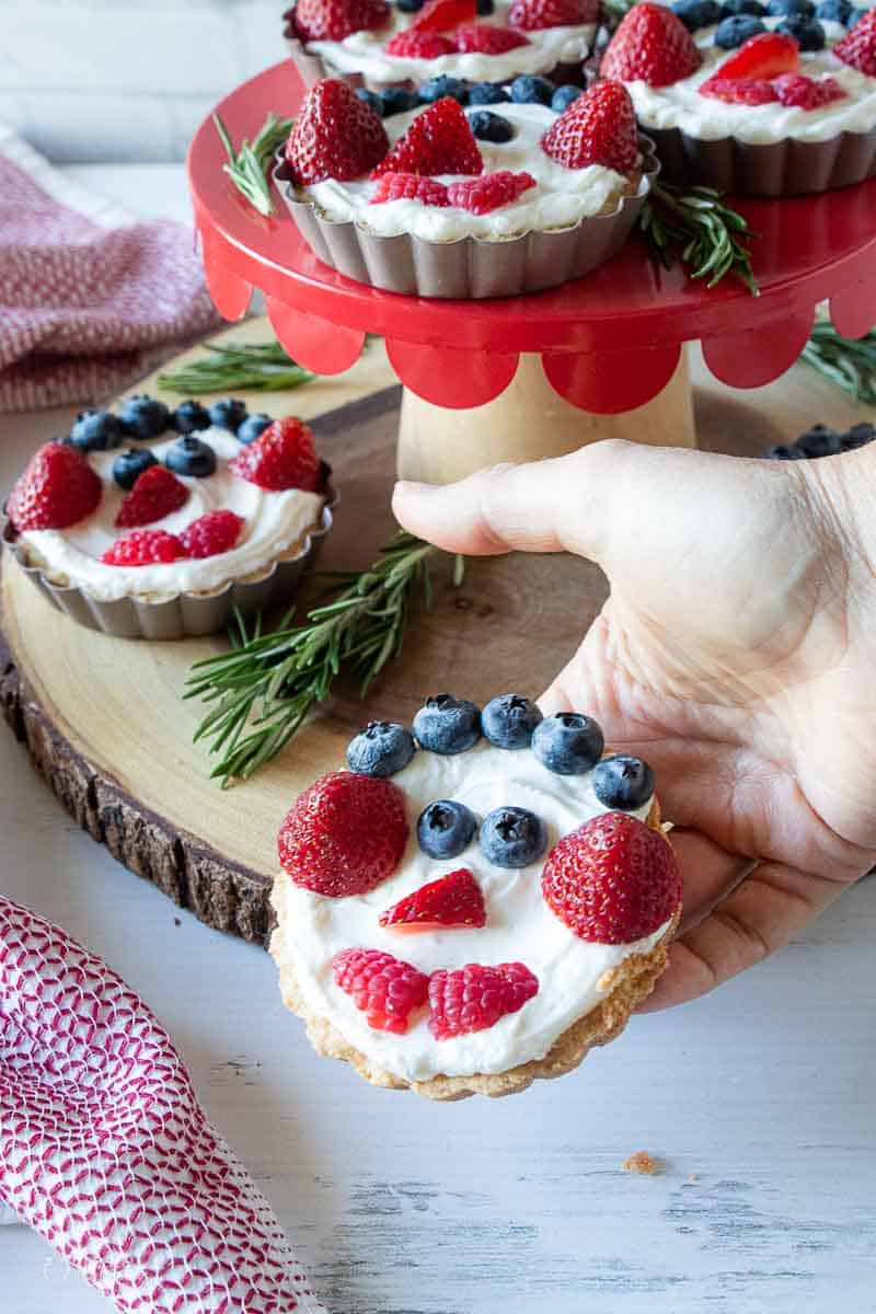 hand holding fruit tart with a snowman face