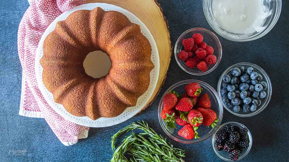 Bundt cake on a serving dish next to fresh berries