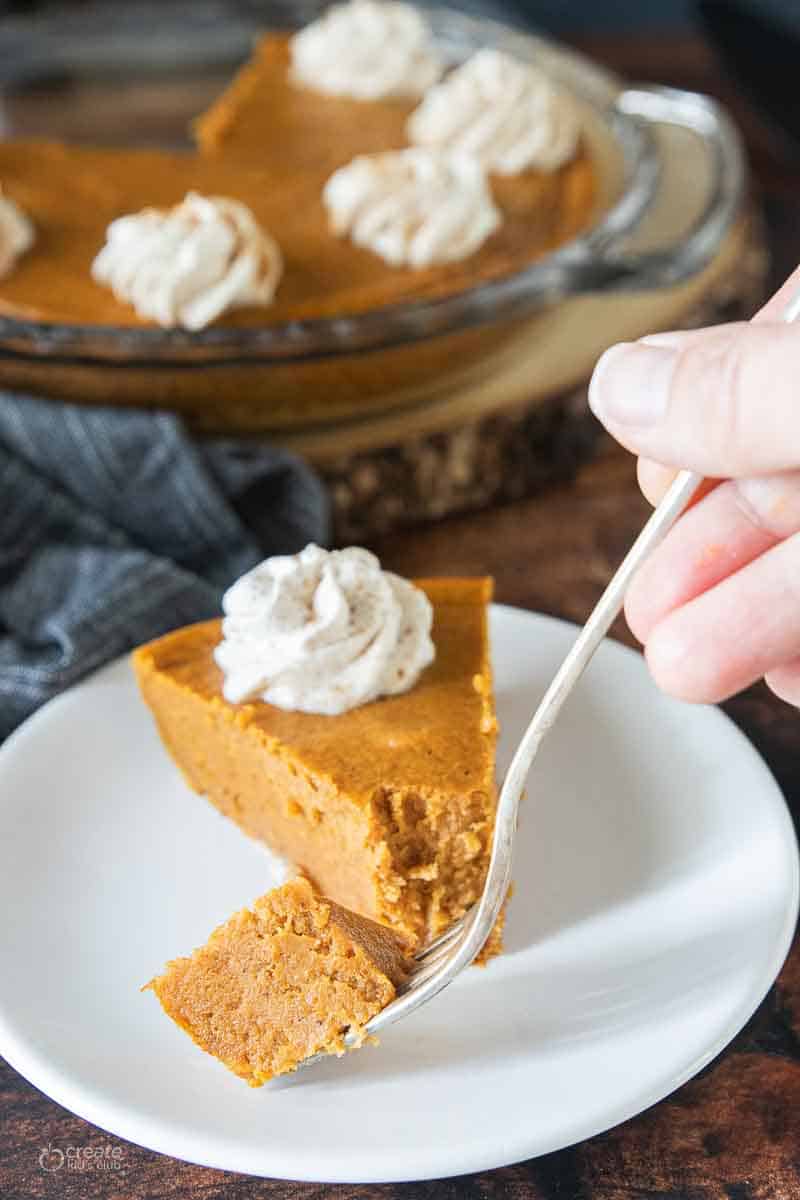 fork scooping a bite of pumpkin pie from plate