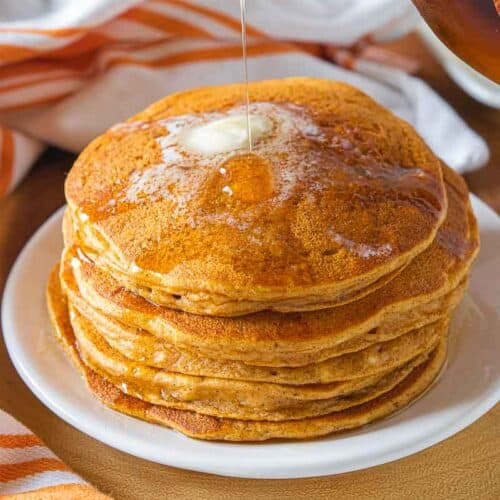 syrup drizzled over stack of pumpkin pancakes
