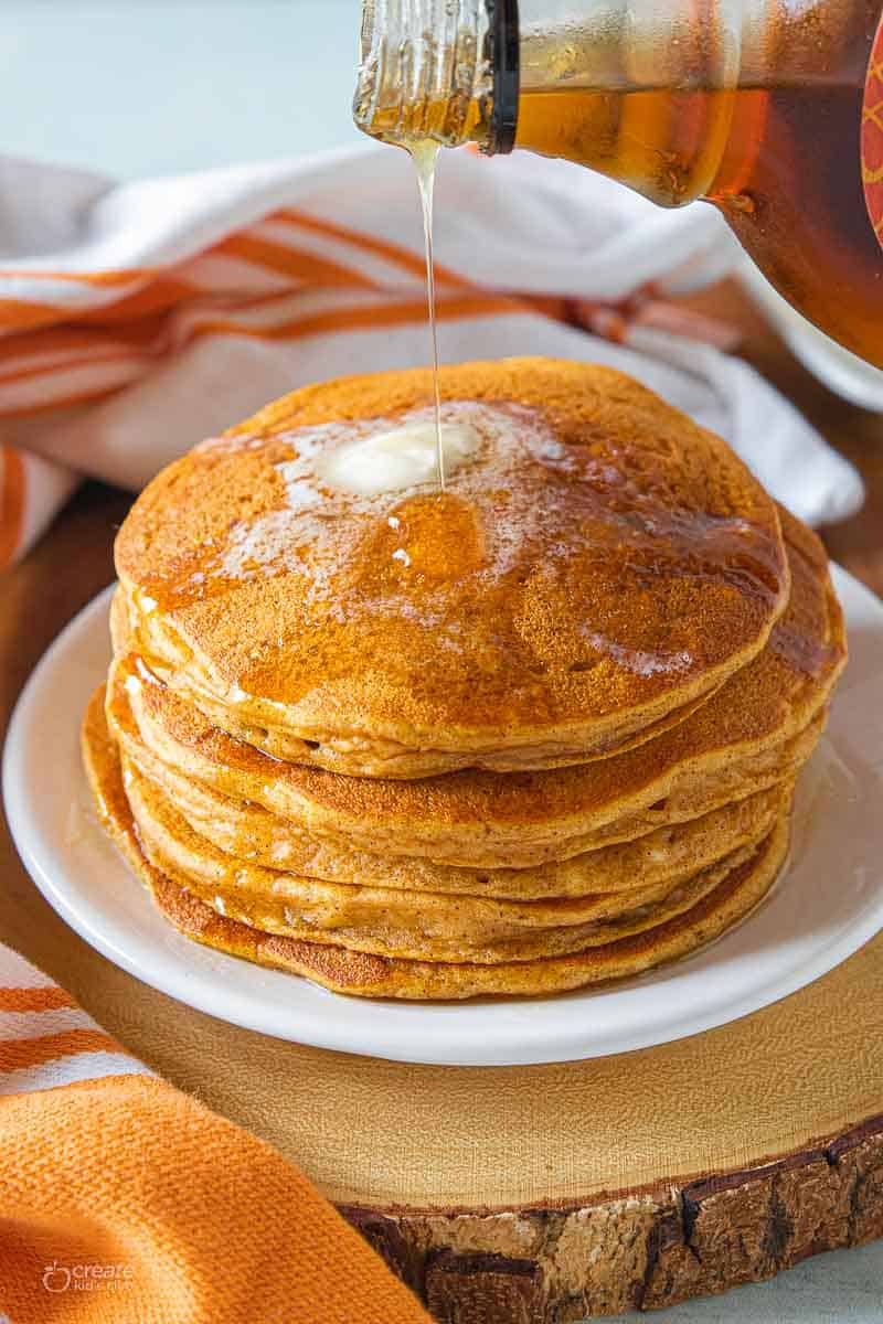 syrup drizzled over stack of pumpkin pancakes