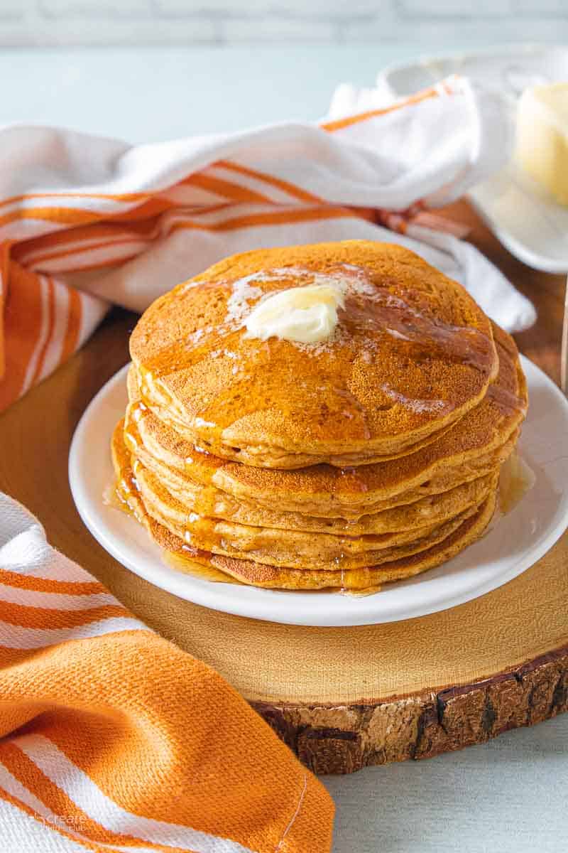 stacked pumpkin pancakes drizzled with syrup and butter