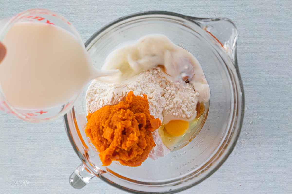 milk slowly poured into bowl with pumpkin pancake ingredients