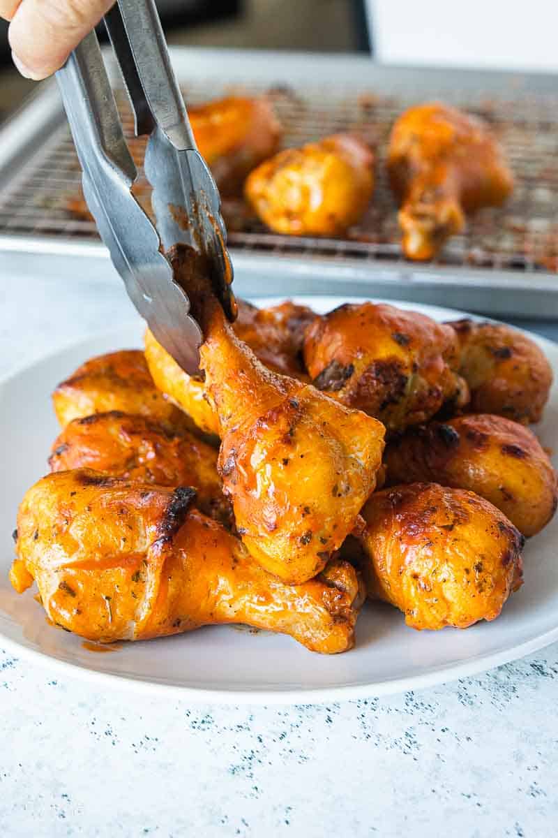 tongs picking up a buffalo chicken leg