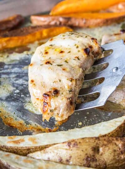 A close up of a pork chop being removed from a sheet pan.