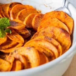 spoon scooping sweet potato slices out of baking dish