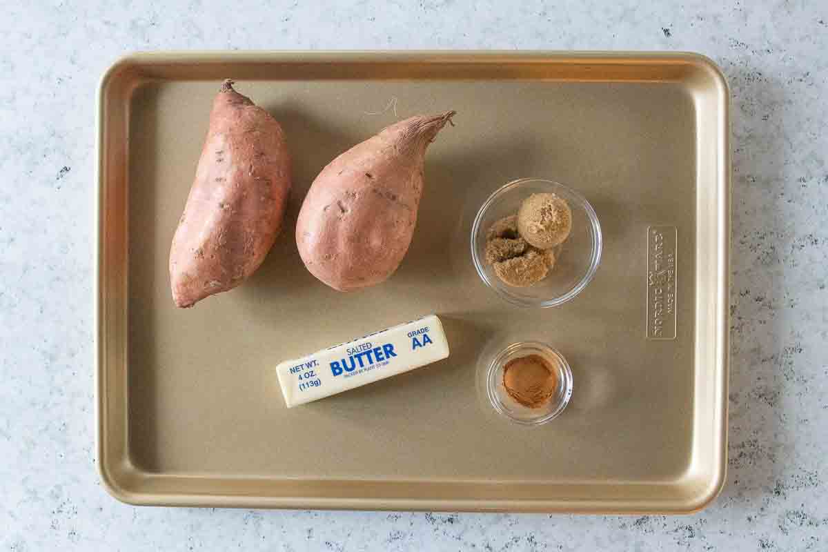 Sweet potatoes, brown sugar, cinnamon, and butter displayed on a tray.