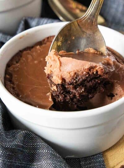 spoon scooping chocolate cake topped with icing from soufflé dish