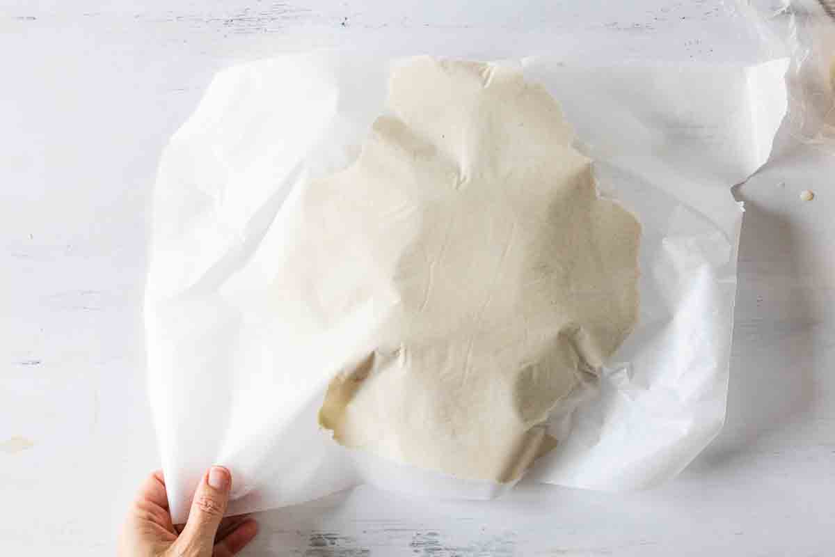 gluten free dough rolled between two sheets of parchment paper