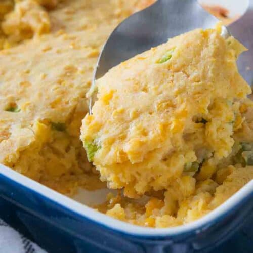 spoon scooping a serving of corn casserole from baking dish
