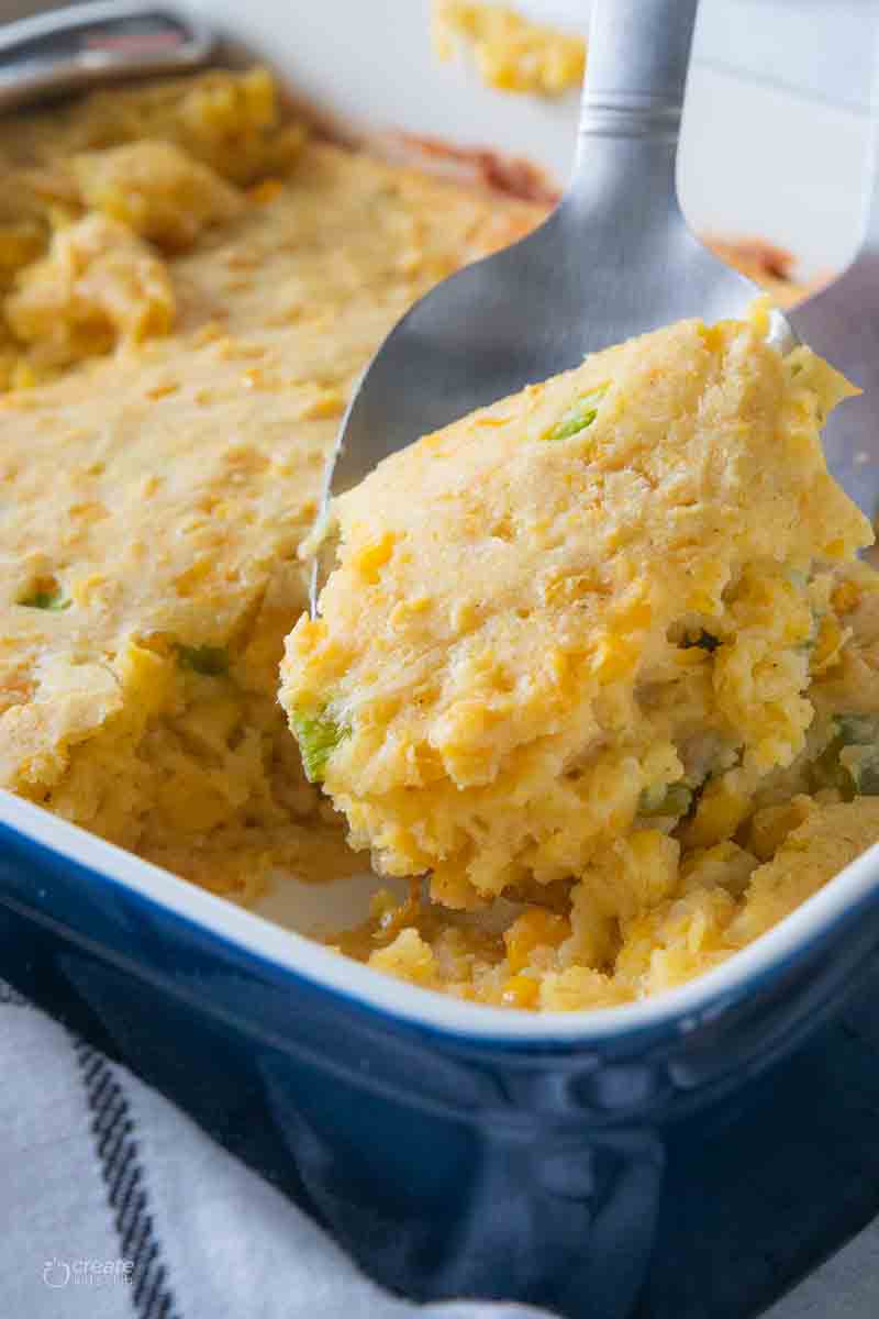 spoon scooping a serving of corn casserole from baking dish