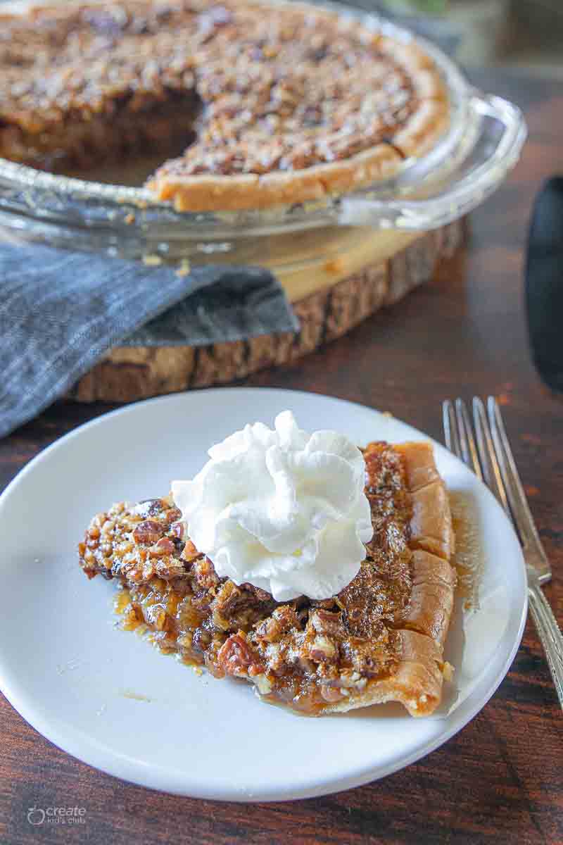 slice of pecan pie on a plate topped with whipped cream