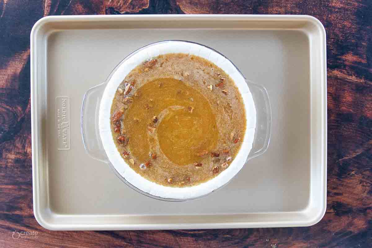 pecan pie batter poured into pie shell in pan on top of baking sheet