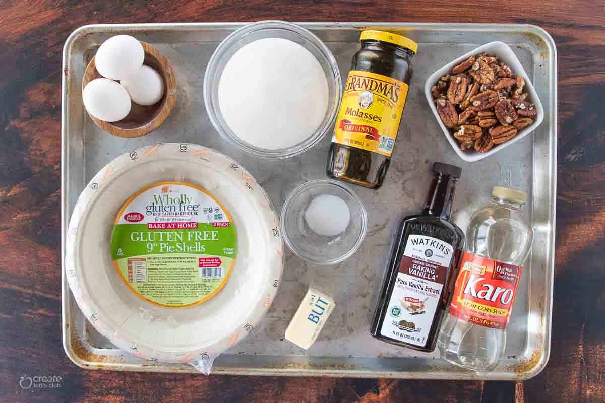 eggs, sugar, molasses, pecans, corn syrup, vanilla, salt, butter and gluten free pie shell on a sheet pan