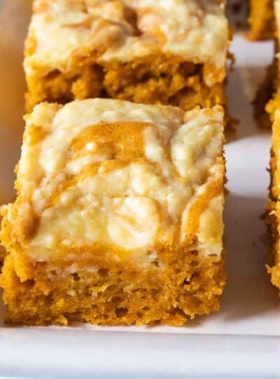 A close up of gluten free pumpkin bars cut into squares on a white tray.