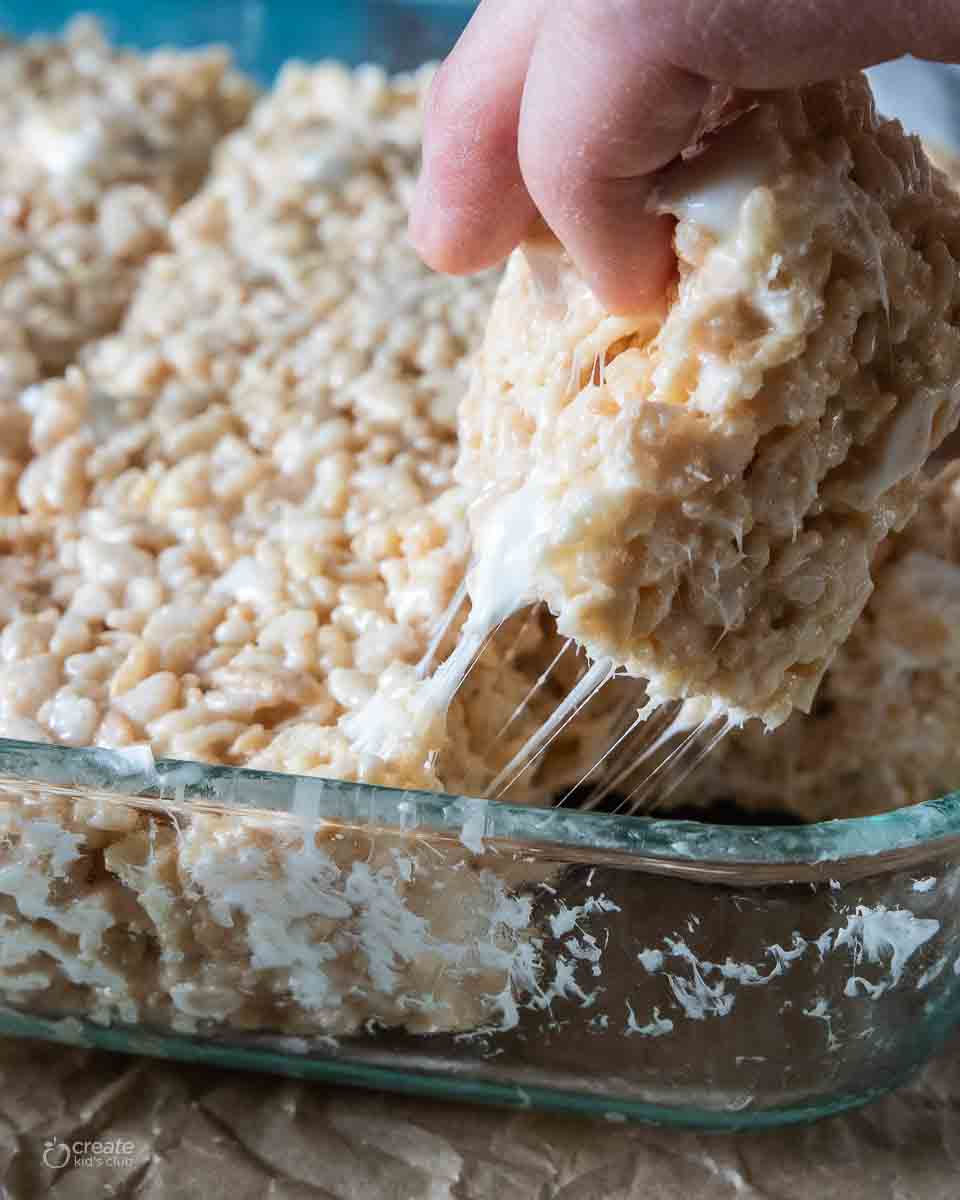 hand pulling rice Krispy treat from baking dish