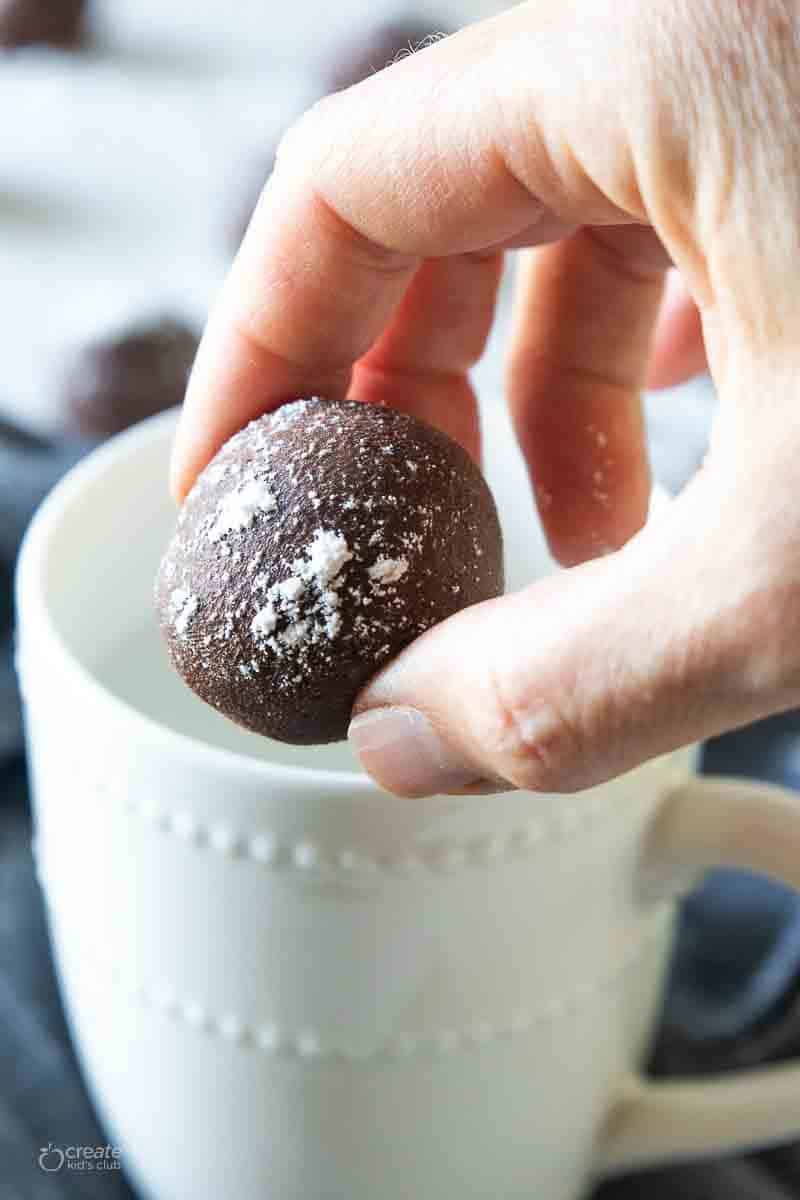 A hot chocolate bomb being placed into a mug.