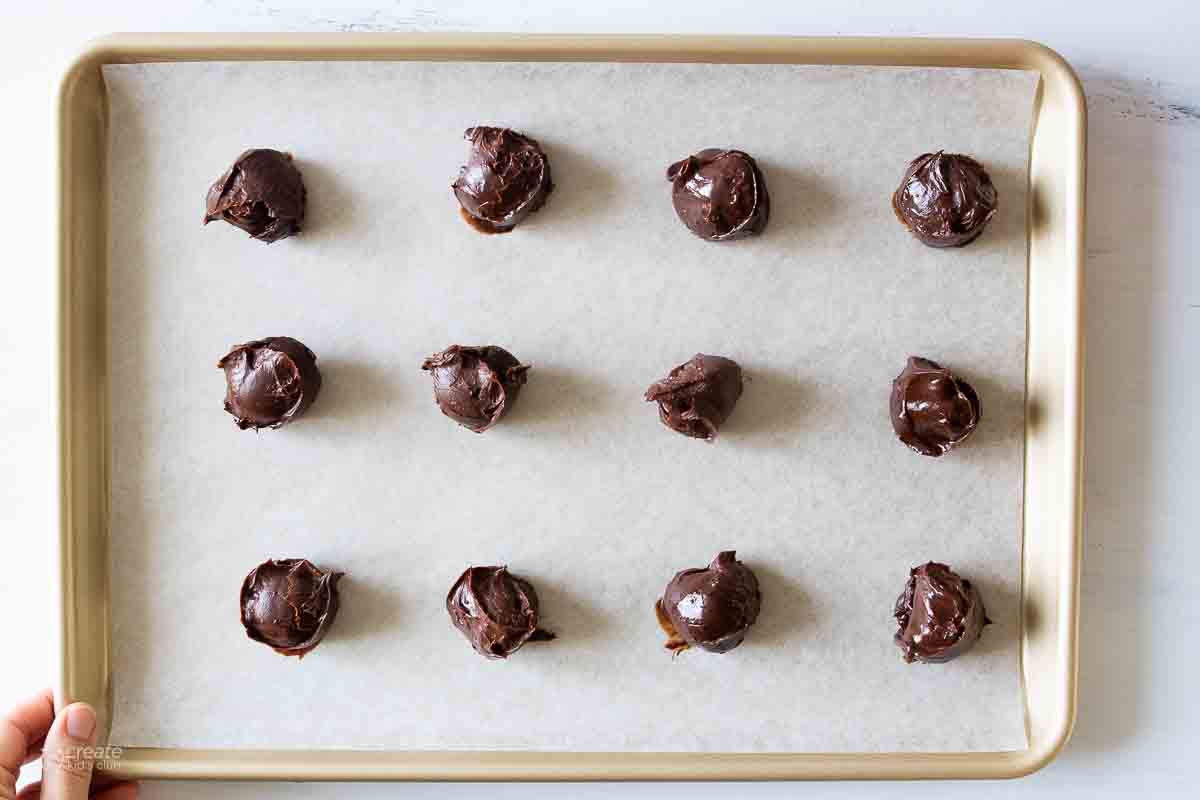 Round balls of chocolate on a baking sheet.