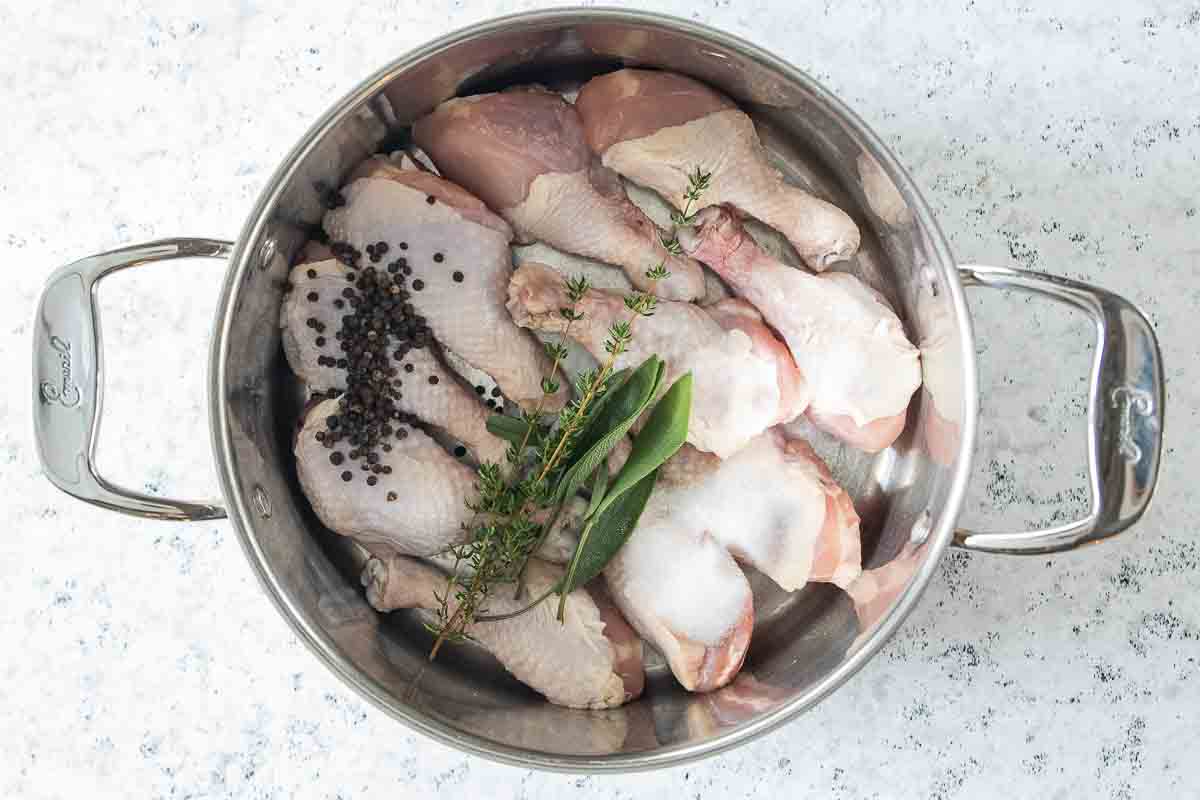 peppercorns, herbs, salt and raw chicken legs in a stock pot