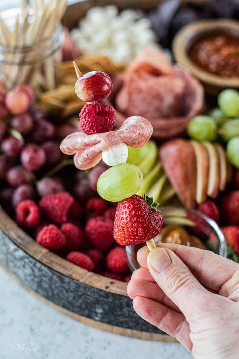 skewer filled with fruit, cheese and meats from a charcuterie board