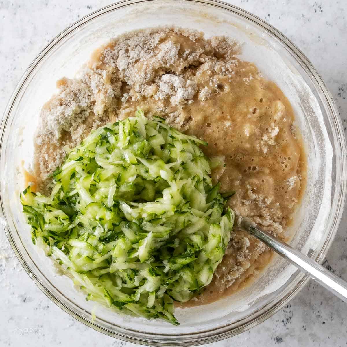 shredded zucchini added to mixing bowl filled with bread batter