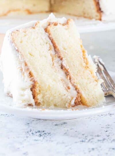 slice of iced whited cake on plate