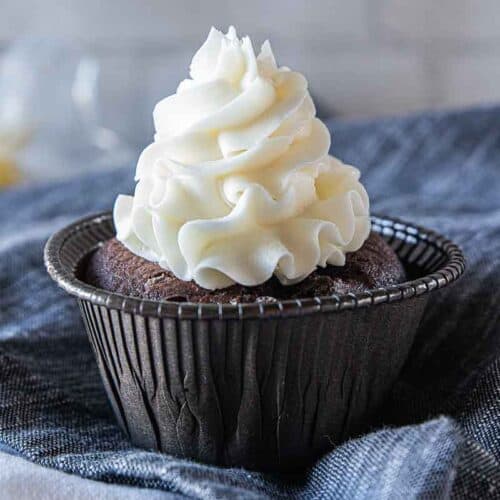 white icing piped on top of chocolate cupcake