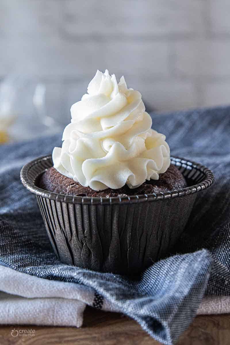 white icing piped on top of chocolate cupcake