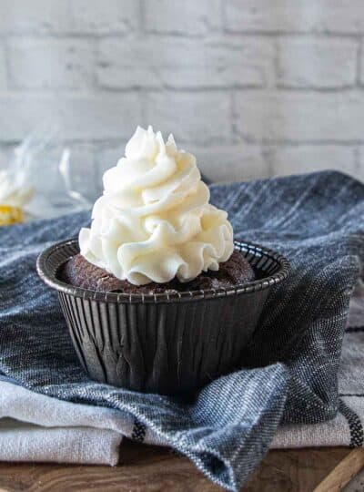 white icing piped on top of chocolate cupcake