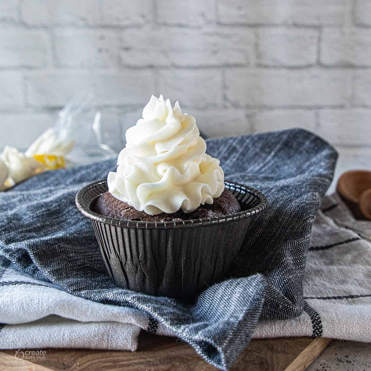 white icing piped on top of chocolate cupcake