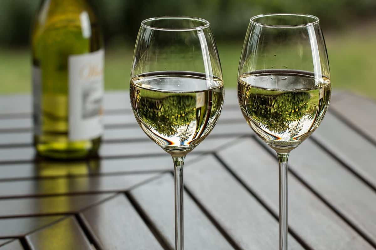 Two glasses of white wine on a table outdoors.