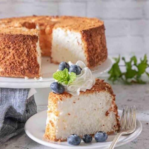 slice of angel food cake on plate topped with whipped topping and berries