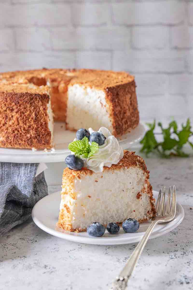 slice of angel food cake on plate topped with whipped topping and berries