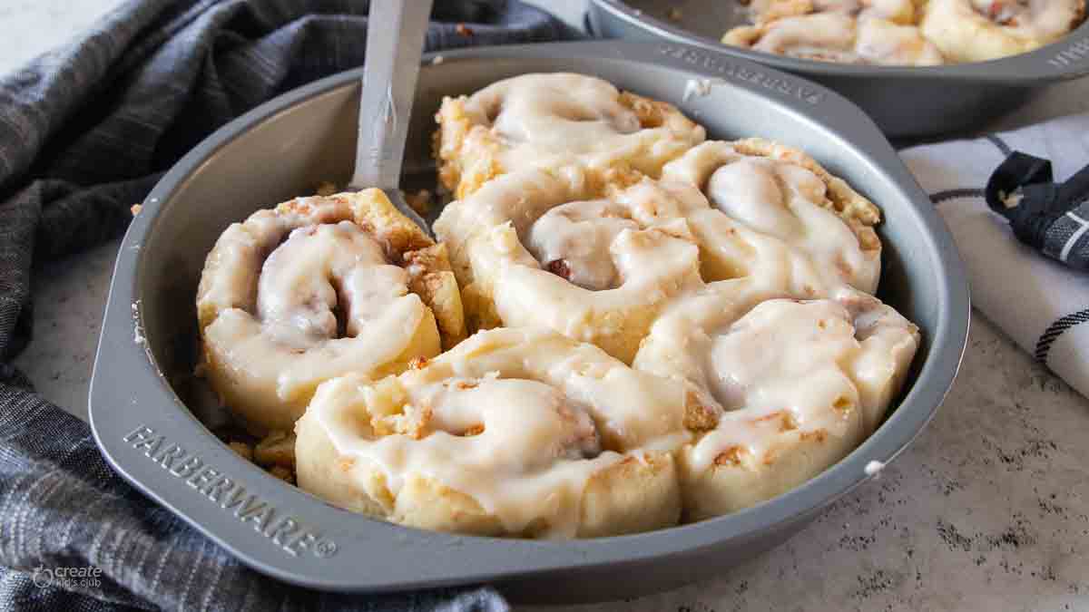 spatula scooping a cinnamon roll from a baking pan