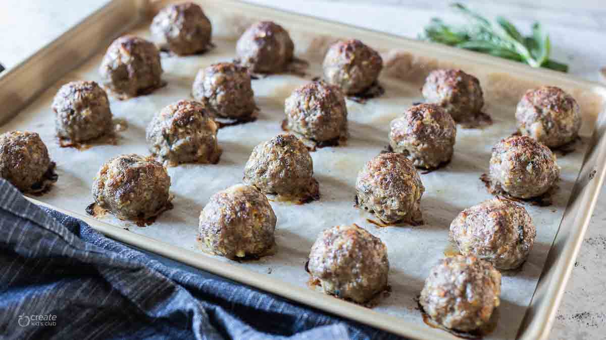 baked meatballs on a parchment lined sheet pan