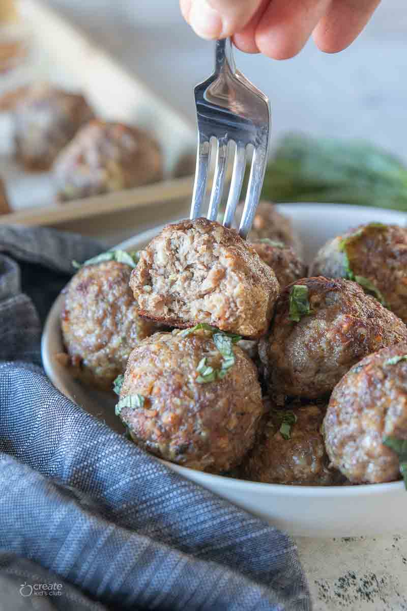 fork scooping up a meatball from a bowl