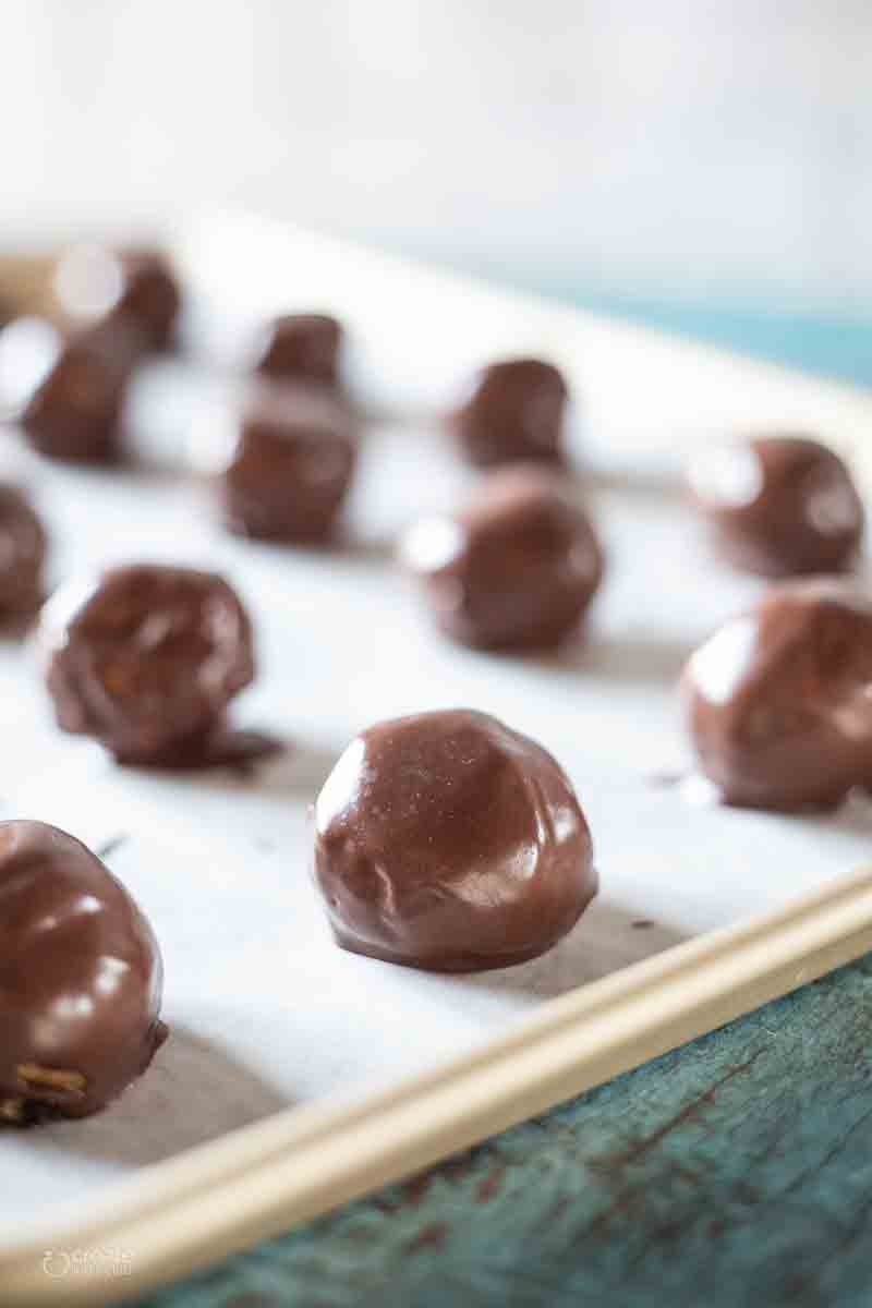 chocolate dipped peanut butter balls on a baking sheet