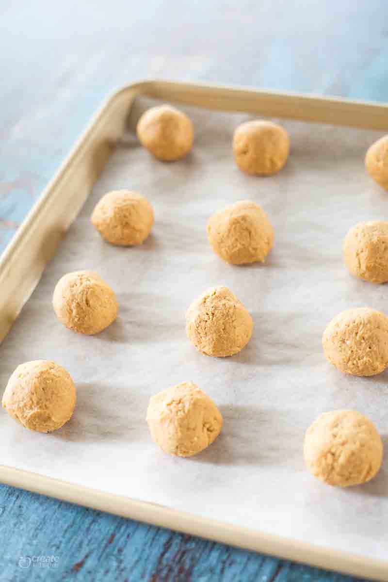 peanut butter balls on a parchment lined baking sheet