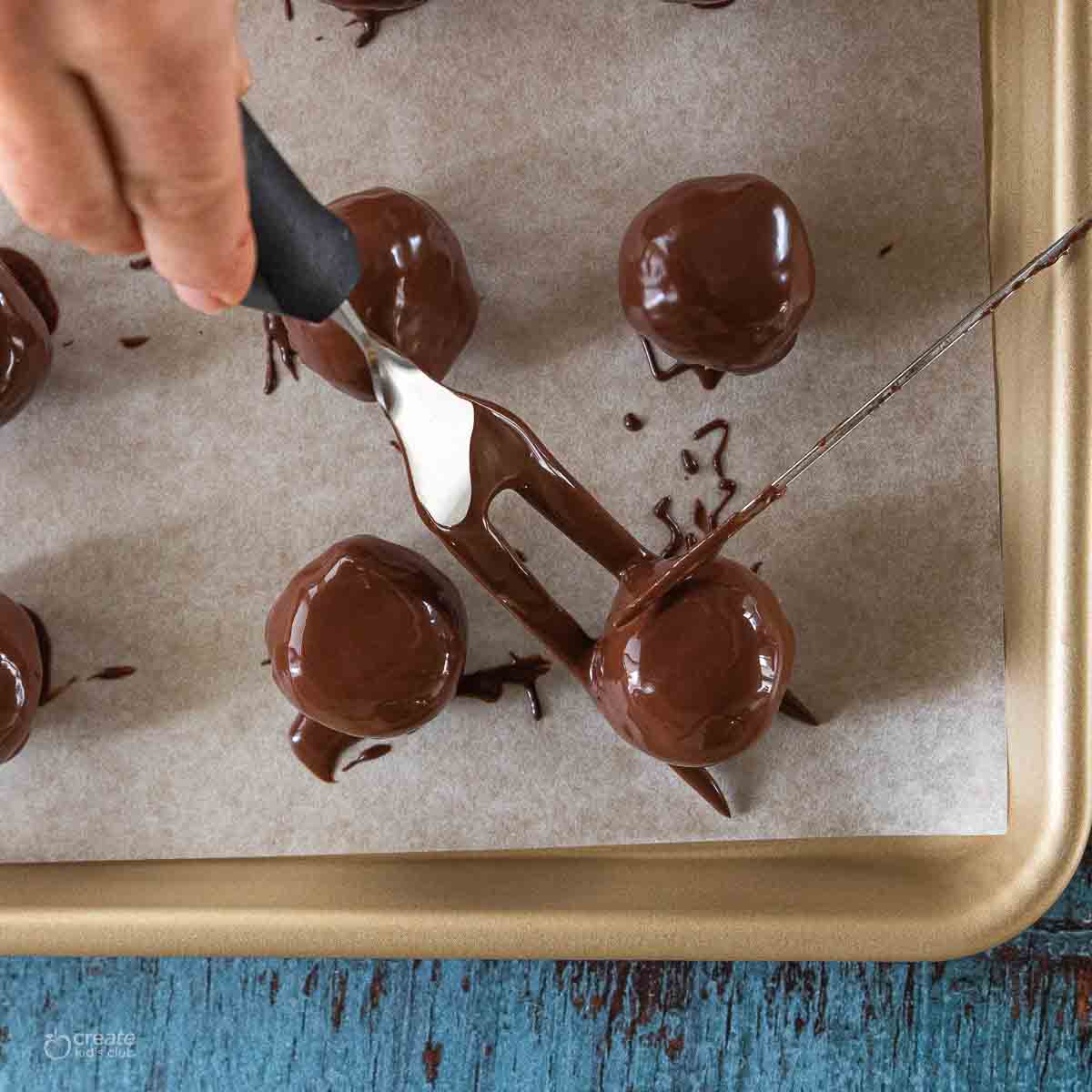 peanut butter balls dipped in chocolate and placed on sheet pan