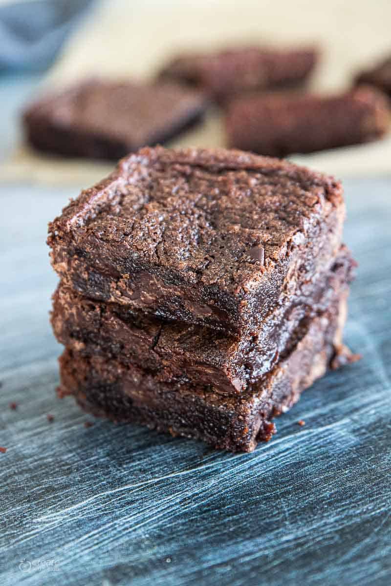 stacked brownies three high on a blue surface.