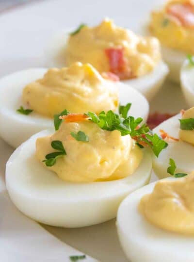 deviled eggs on platter garnished with fresh herbs