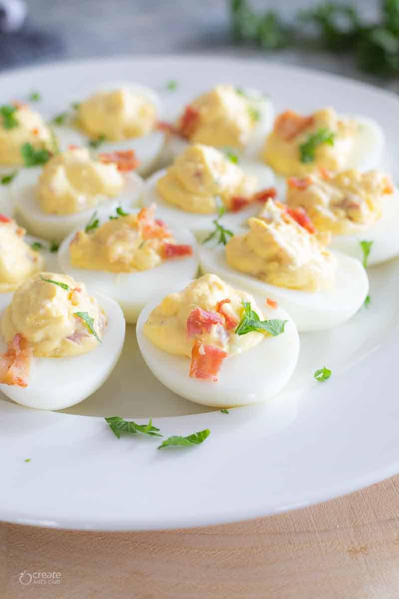 dairy free deviled eggs topped with bacon bits and herbs